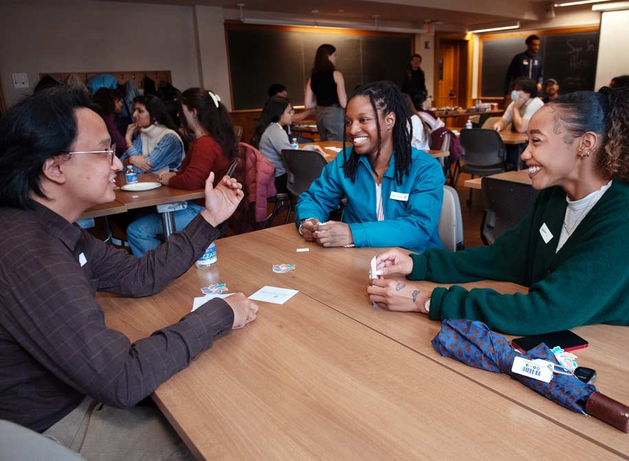 Three diverse students sitting around a table engaged in a conversation